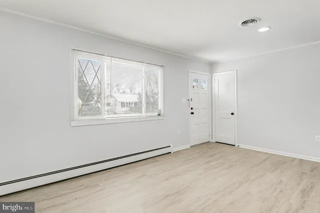 a view of an empty room with wooden floor and a window