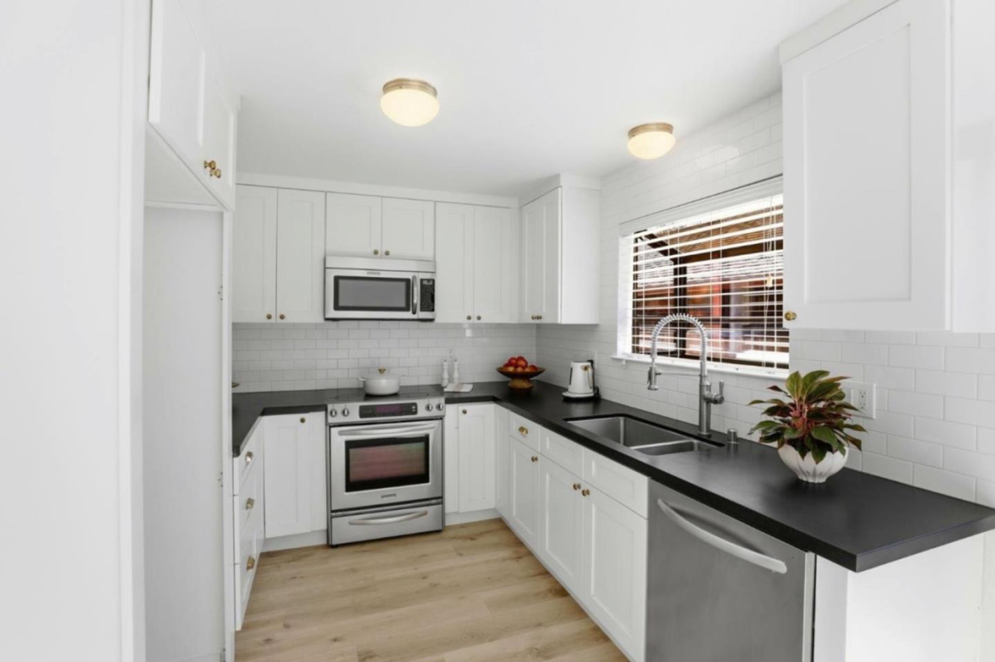 1555 Hecker Pass Road, Unit H102 Gilroy, CA 95020 - Photo 14 of 34 a kitchen with granite countertop stainless steel appliances a sink cabinets and a window