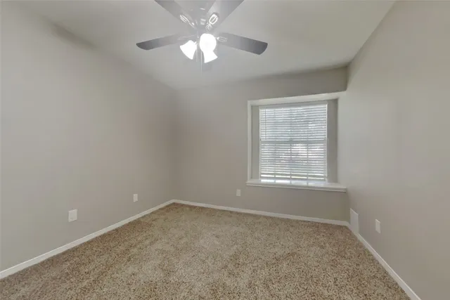 an empty room with a chandelier fan and windows