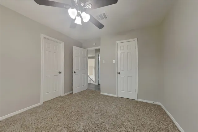an empty room with a chandelier fan and closet area