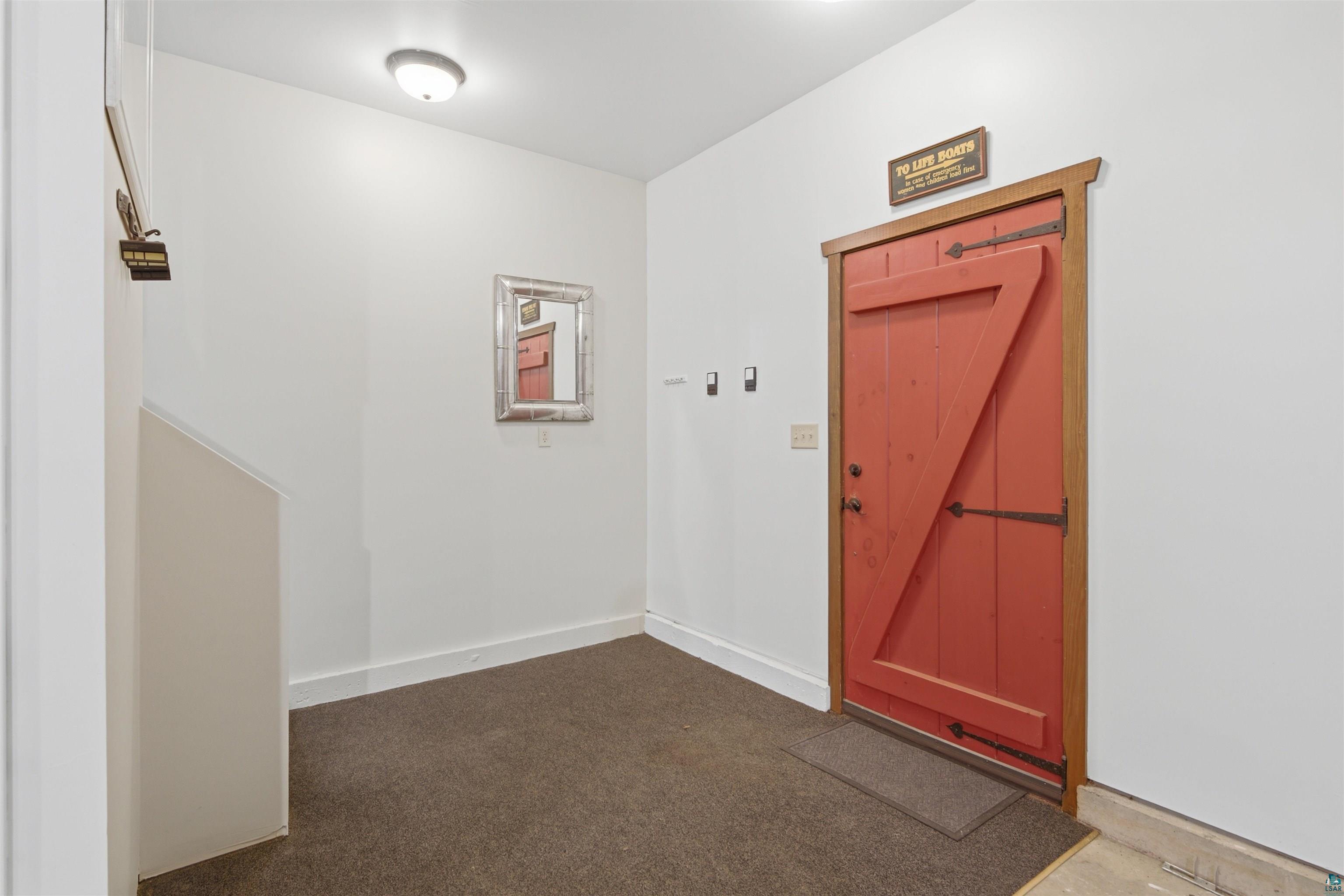 86270 Meyers-Olson Road Bayfield, WI 54814 - Photo 20 of 33 Entry area featuring a red barn-style door with dark hardware, white walls, and dark carpet flooring