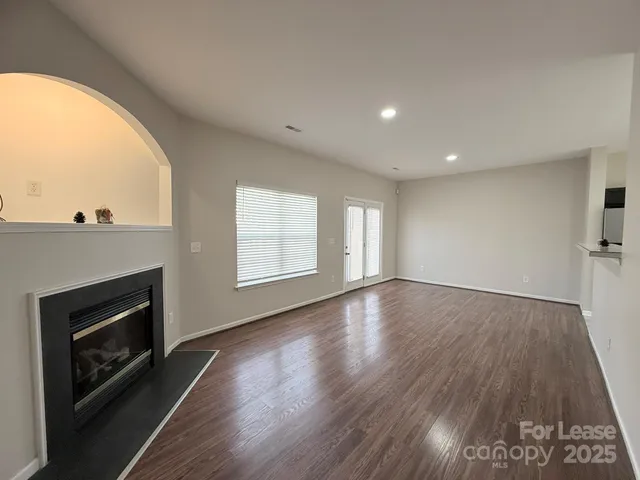 an empty room with wooden floor fireplace and windows