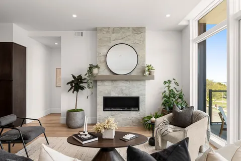 a living room with furniture a fireplace a floor to ceiling window and potted plant