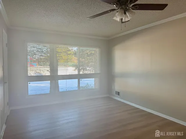 an empty room with wooden floor fan and windows