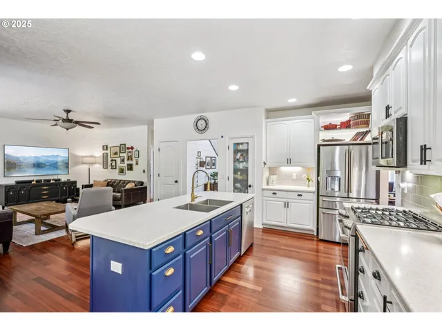 a kitchen with stainless steel appliances kitchen island granite countertop a refrigerator a stove and a wooden floors