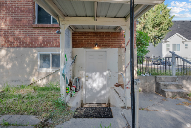 1275 North Geneva Road Provo, UT 84601 - Photo 20 of 25 Covered outdoor entryway featuring a white exterior door, a brick wall accent, and concrete steps