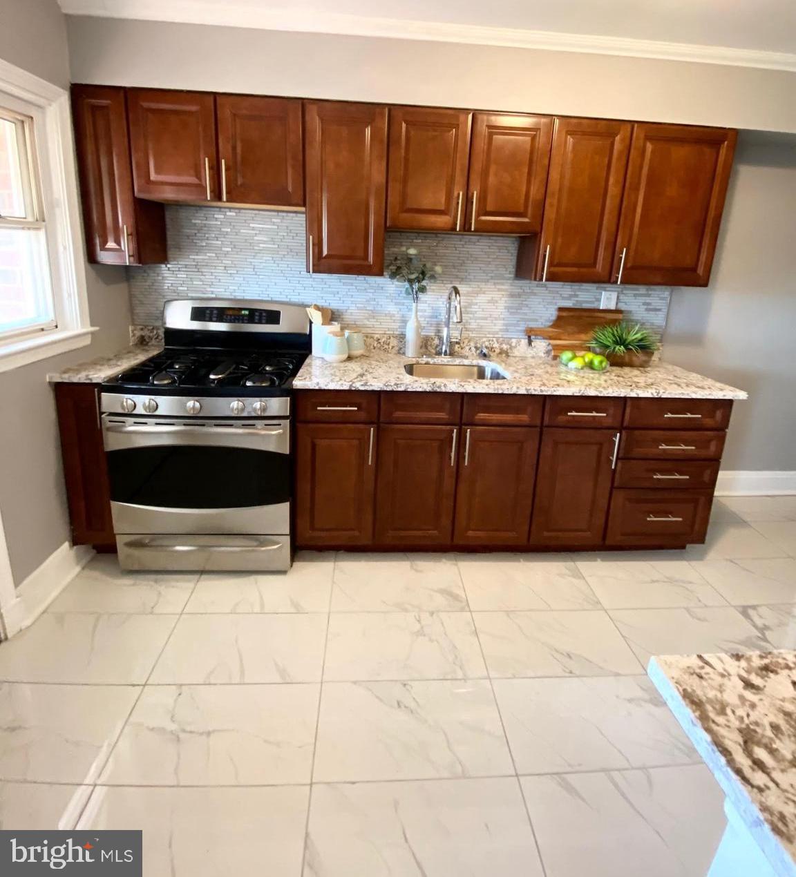 5019 Schaub Avenue Baltimore, MD 21206 - Photo 11 of 34 a kitchen with granite countertop a stove a sink a counter space and cabinets
