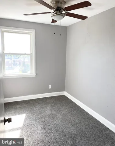 an empty room with a window and a ceiling fan