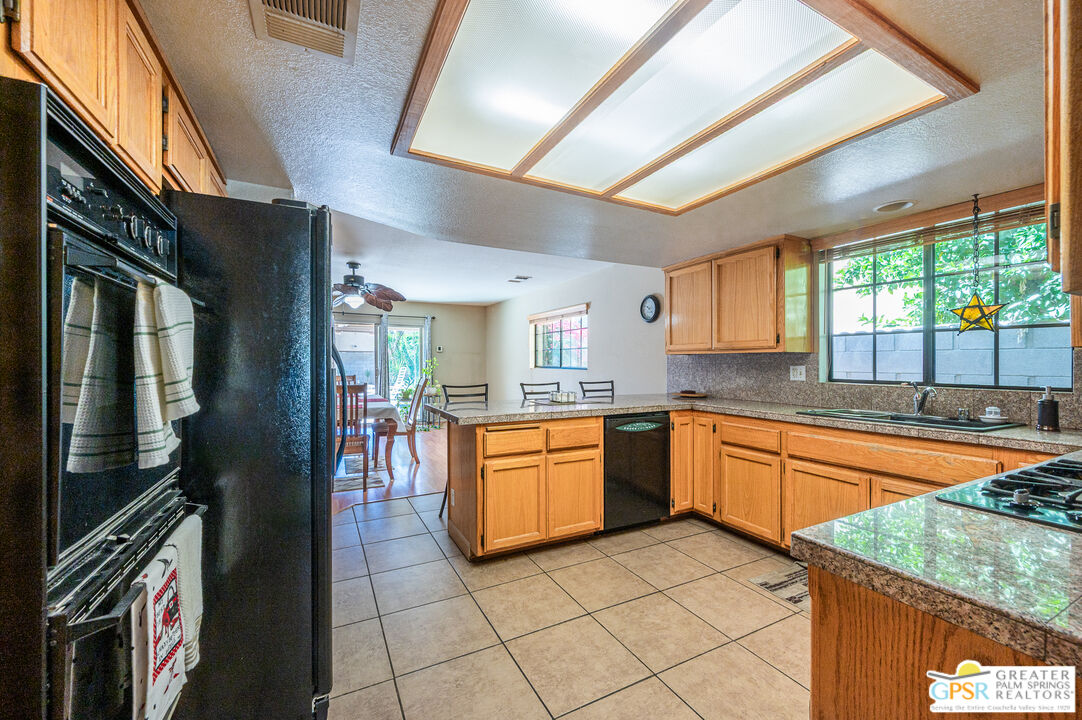 68655 Durango Road Cathedral City, CA 92234 - Photo 11 of 36 a kitchen with stainless steel appliances granite countertop a refrigerator a sink dishwasher a stove and white countertops with wooden floor