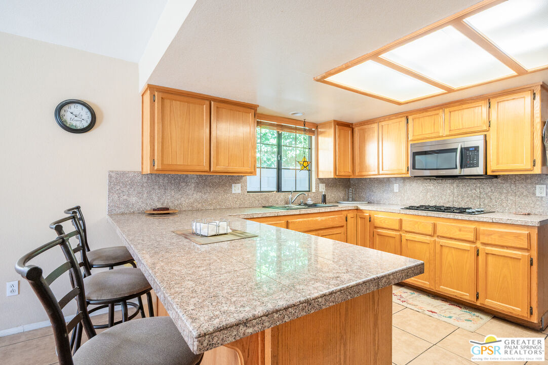 68655 Durango Road Cathedral City, CA 92234 - Photo 10 of 36 a kitchen with granite countertop a sink chairs and window