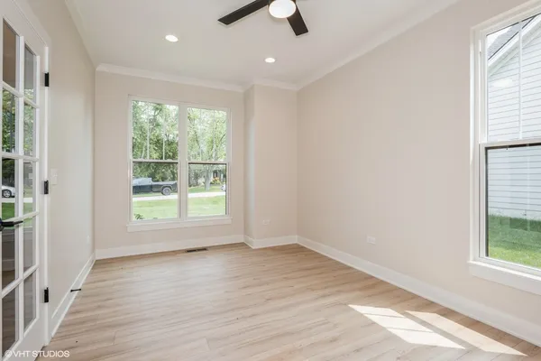an empty room with wooden floor cabinet and windows