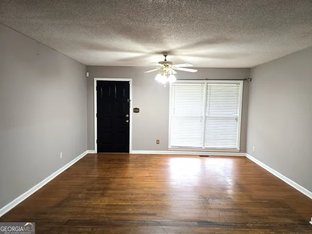 a view of an empty room with wooden floor and a window