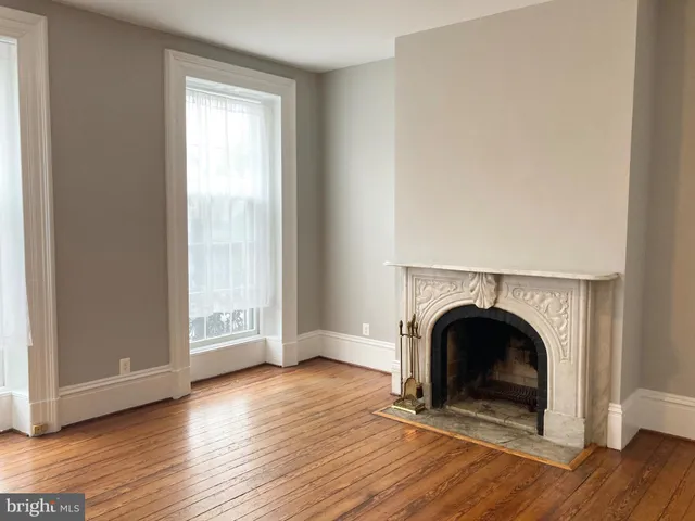 an empty room with fireplace and wooden floor