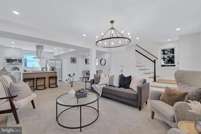 a living room with furniture a kitchen view and a chandelier