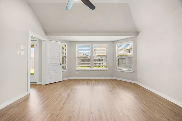 an empty room with wooden floor cabinet and windows