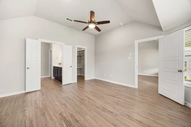 an empty room with wooden floor cabinet and windows
