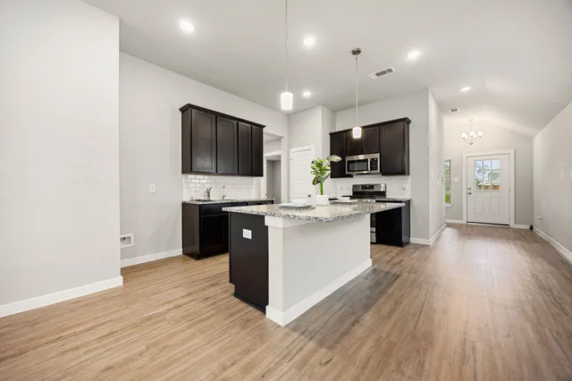 a large kitchen with stainless steel appliances granite countertop a large counter top a sink and a stove