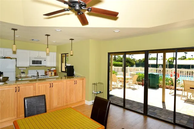 a living room with stainless steel appliances wooden floor dining table and a large window