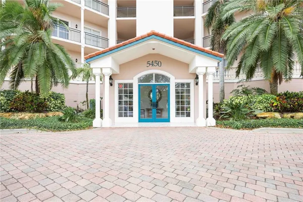 a front view of a multi story residential apartment building with yard and entryway