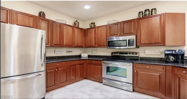a kitchen with granite countertop a refrigerator stove and microwave