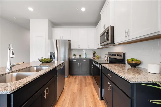 a kitchen with granite countertop lots of stainless steel appliances granite countertop a sink stove and refrigerator