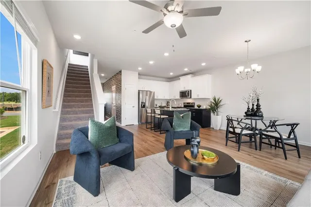 a living room with furniture kitchen view and a large window