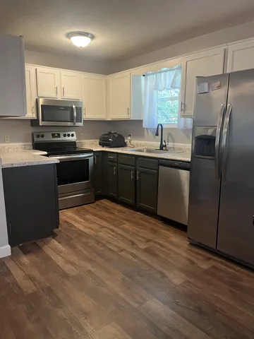 a kitchen with granite countertop a refrigerator and steel cabinets