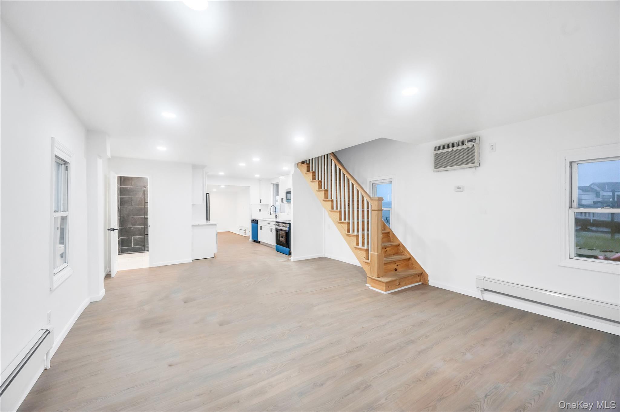 21 Van Brunt Road Queens, NY 11693 - Photo 4 of 17 Unfurnished living room with a baseboard radiator, light wood-style flooring, stairway, recessed lighting, and a wall mounted air conditioner