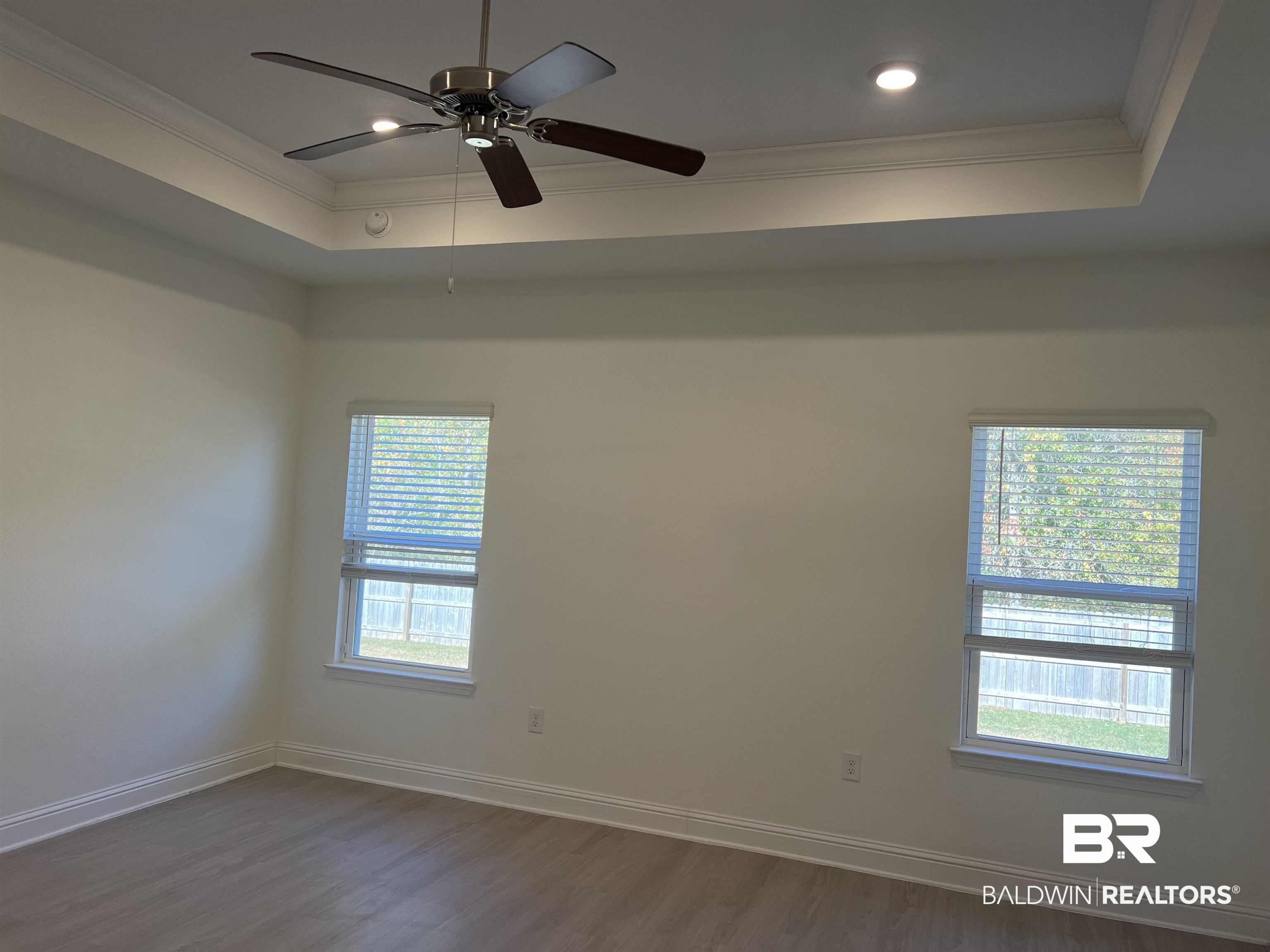 8855 Calverton Street Foley, AL 36535 - Photo 48 of 76 Empty room with ceiling fan, a raised ceiling, ornamental molding, and dark wood-type flooring