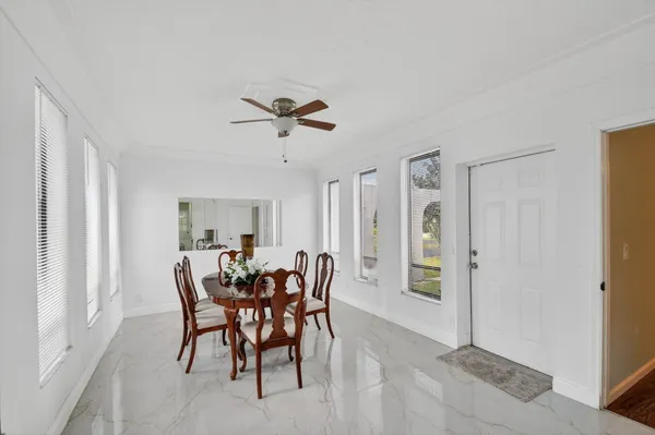 an empty room with wooden floor chandelier fan and windows