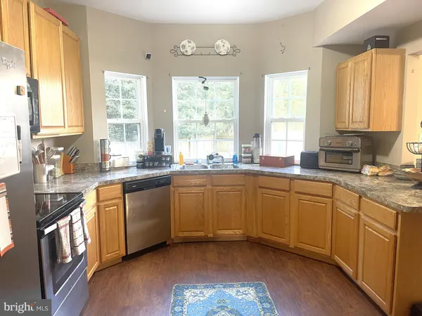 a kitchen with stainless steel appliances granite countertop a sink a stove cabinets counter space and windows