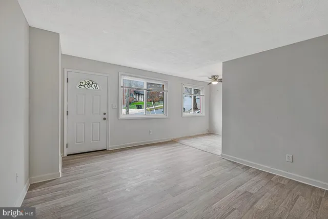 an empty room with wooden floor and windows