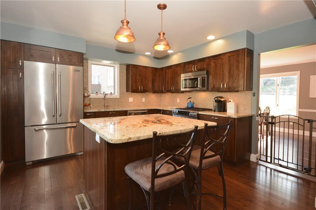 1222 Driftwood Drive Mt. Lebanon, PA 15243 - Photo 12 of 25 a kitchen with stainless steel appliances granite countertop a refrigerator a sink dishwasher a dining table and chairs with wooden floor