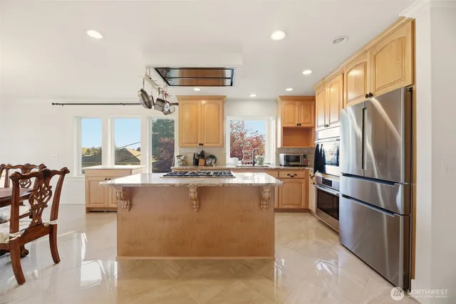 a kitchen with stainless steel appliances a refrigerator a stove a dining table and chairs