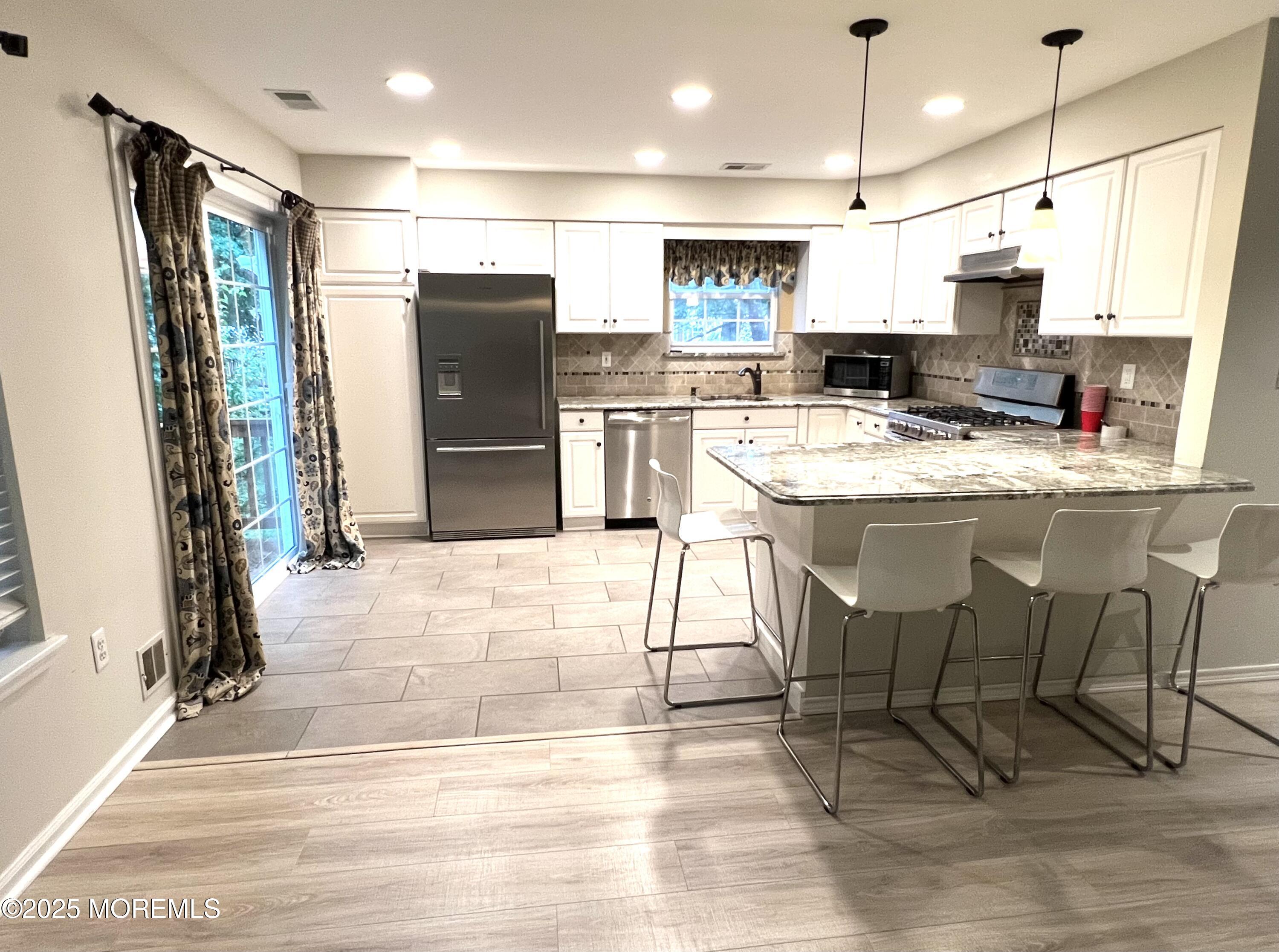 21 Durant Avenue, Unit 145 Holmdel, NJ 07733 - Photo 4 of 25 a kitchen with stainless steel appliances kitchen island granite countertop a refrigerator and a stove top oven