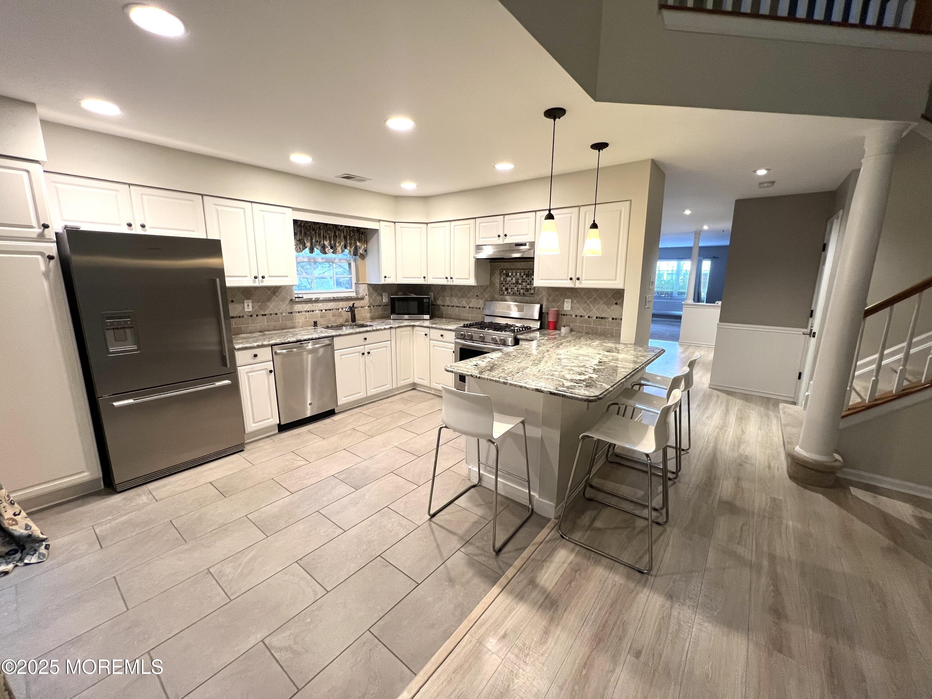 21 Durant Avenue, Unit 145 Holmdel, NJ 07733 - Photo 5 of 25 a kitchen with stainless steel appliances kitchen island granite countertop a refrigerator a stove a sink a dining table and chairs with wooden floor