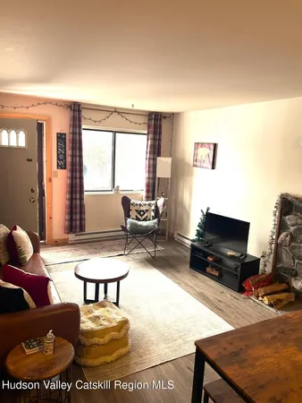 a living room with furniture and a flat screen tv with kitchen view