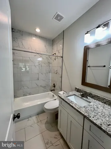 a bathroom with a granite countertop sink mirror vanity and a toilet