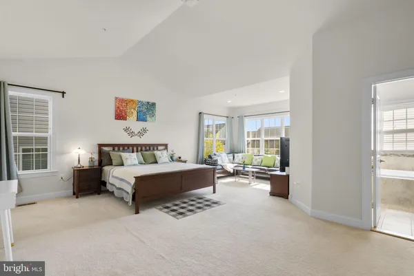 a bedroom with a bed a table and windows