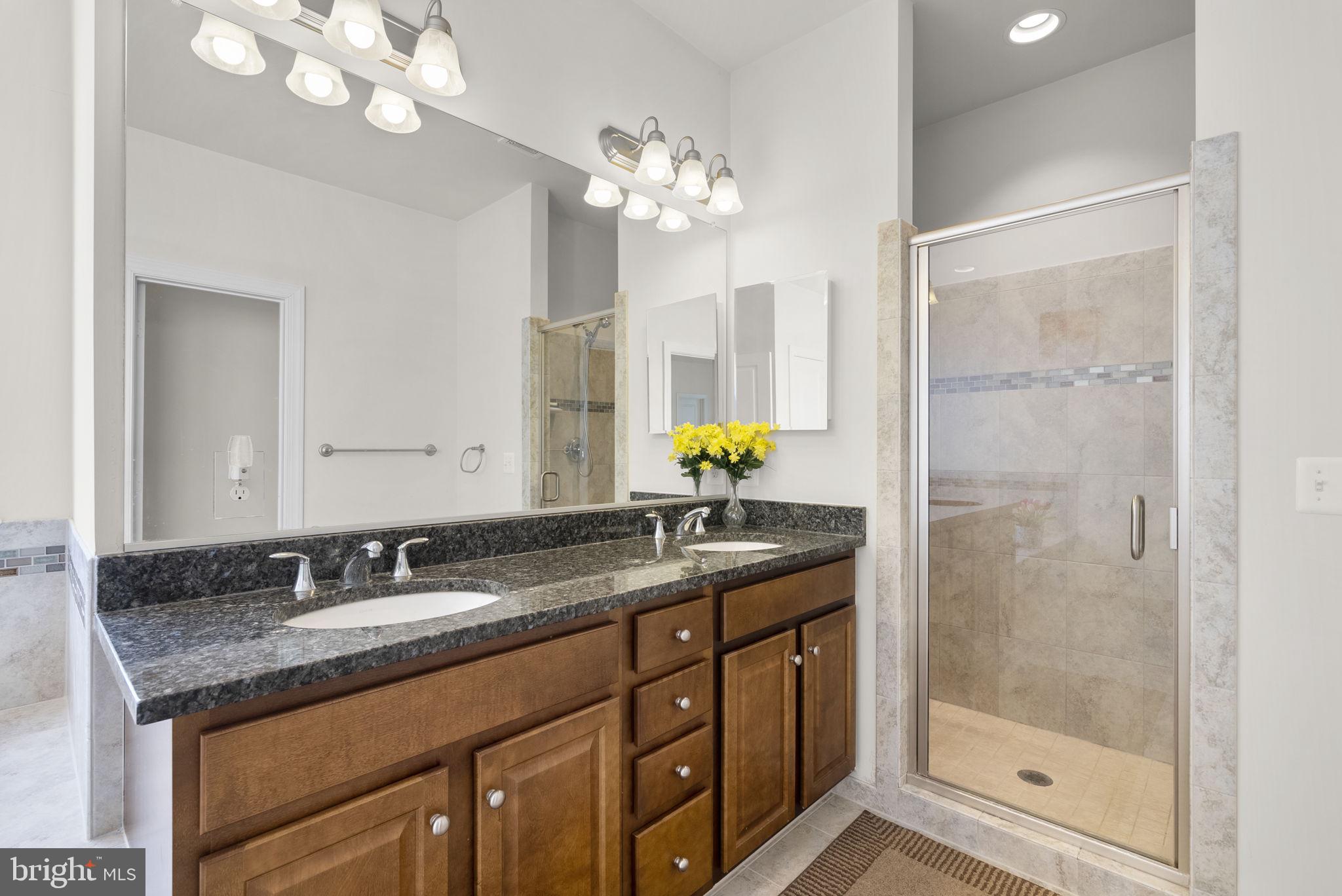 22403 Newcut Road Clarksburg, MD 20871 - Photo 42 of 78 a bathroom with a granite countertop shower a sink and a mirror