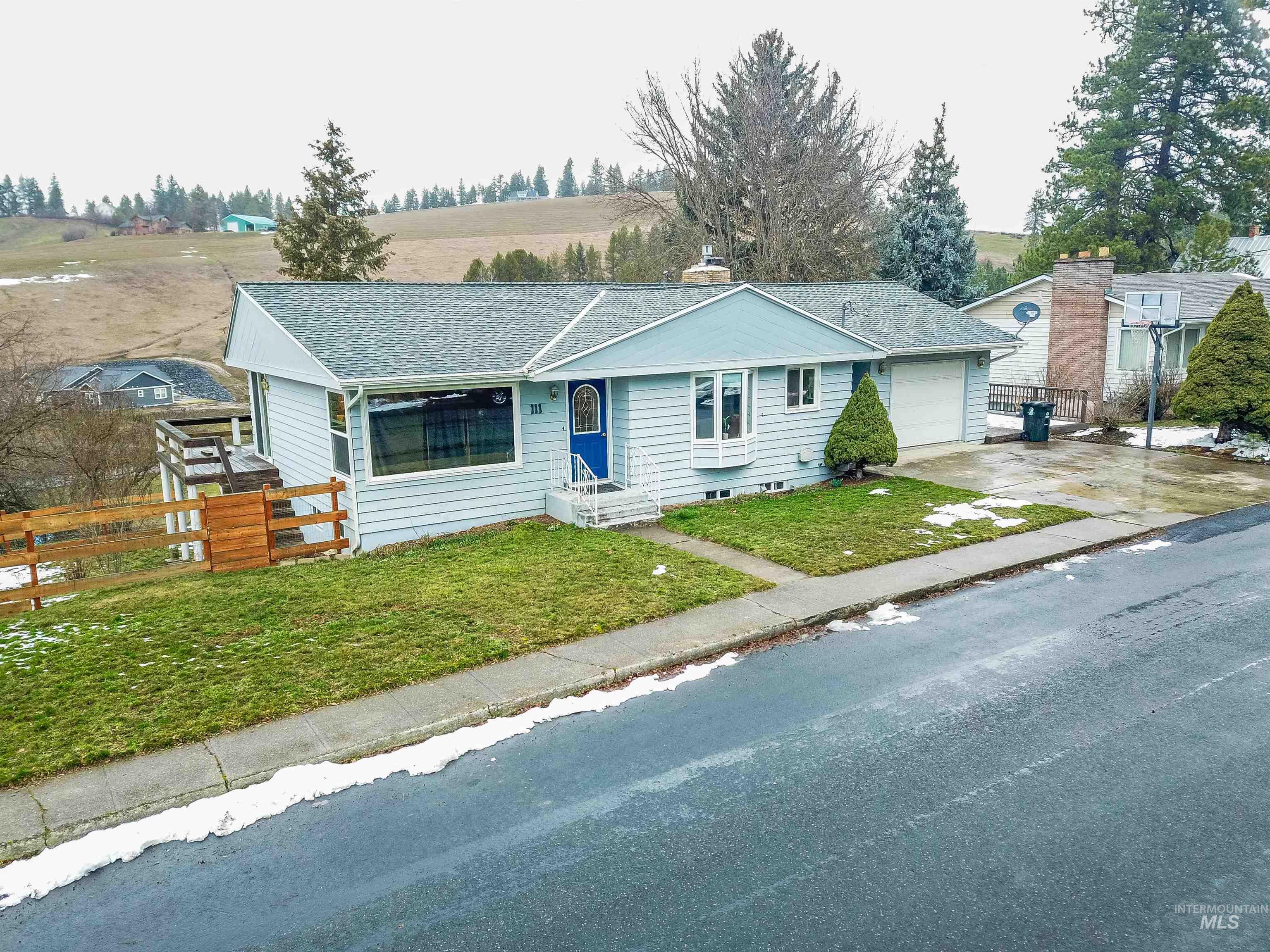 Ranch-style home featuring a garage, concrete driveway, a shingled roof, and a chimney
