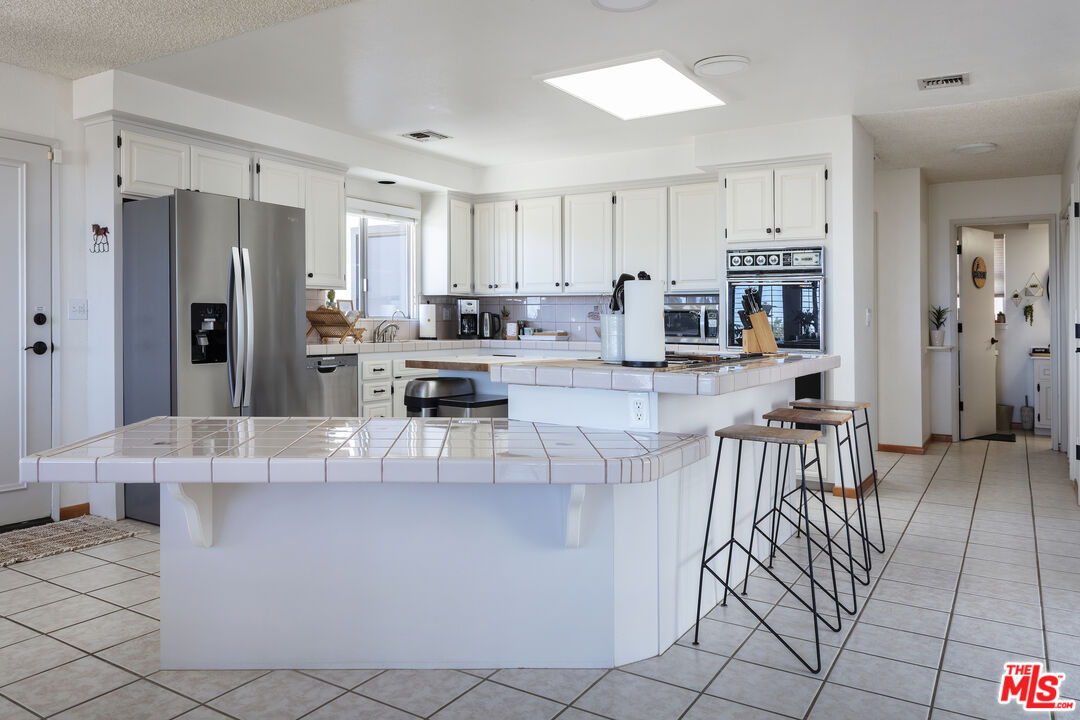 56434 Cobalt Road Yucca Valley, CA 92284 - Photo 36 of 75 a view of kitchen with stainless steel appliances kitchen island granite countertop dining table chairs and a refrigerator