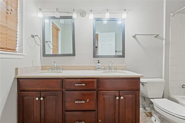 a bathroom with a granite countertop sink a toilet and a mirror