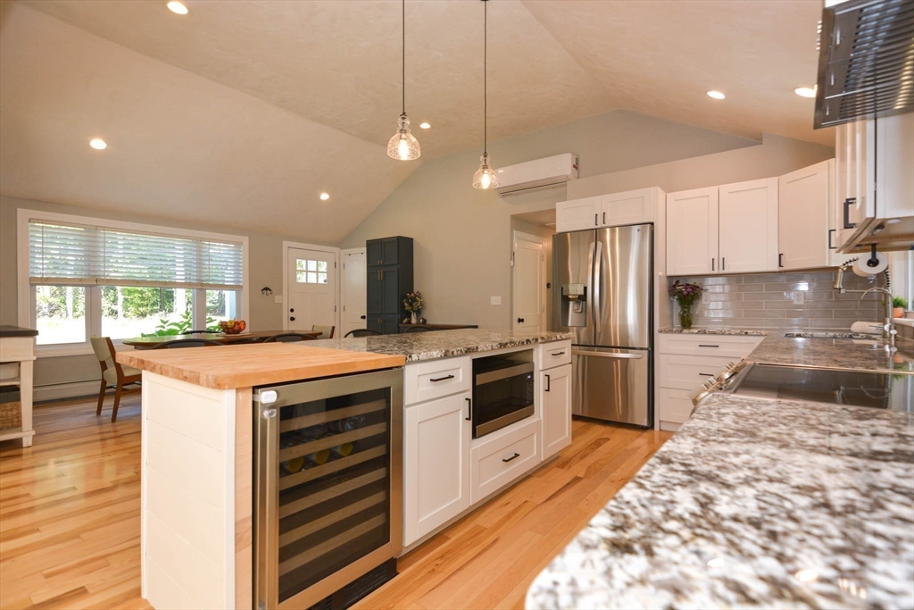 57 Parham Road Tyngsborough, MA 01879 - Photo 5 of 42 a kitchen with kitchen island a stove a sink a refrigerator and white cabinets with wooden floor