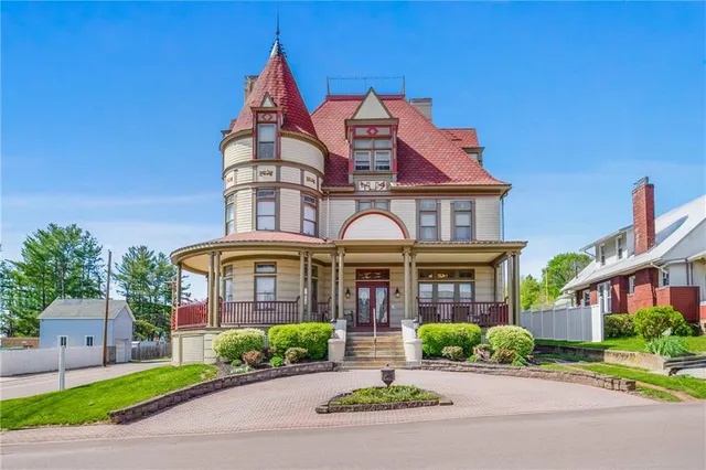 a front view of a building with garden and parking