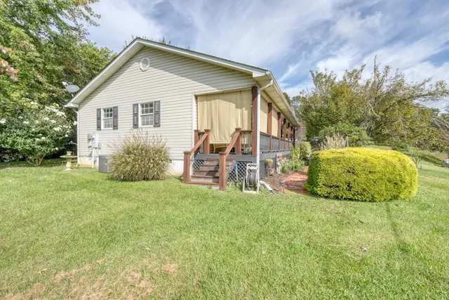 a view of a backyard with table and chairs potted plants and large tree