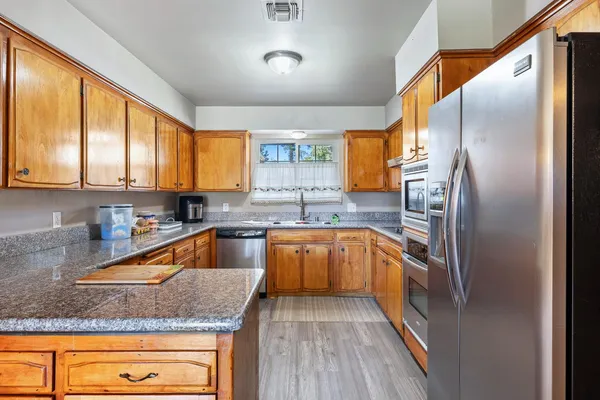 a kitchen with stainless steel appliances granite countertop a sink a stove and a refrigerator
