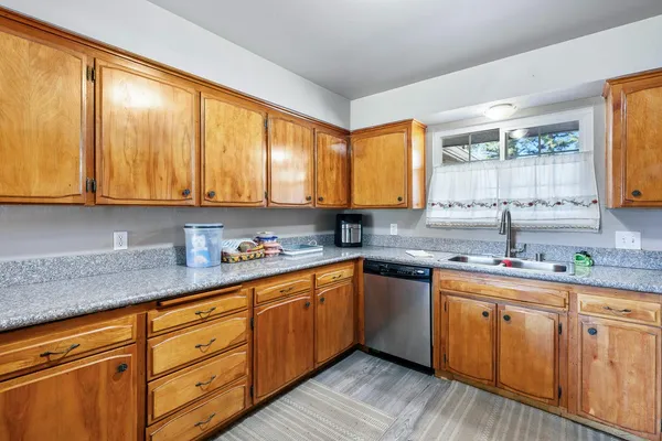 a kitchen with stainless steel appliances granite countertop wooden cabinets a sink and dishwasher with wooden floor
