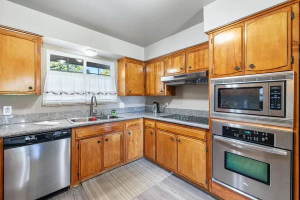 a kitchen with stainless steel appliances granite countertop a sink a stove and cabinets