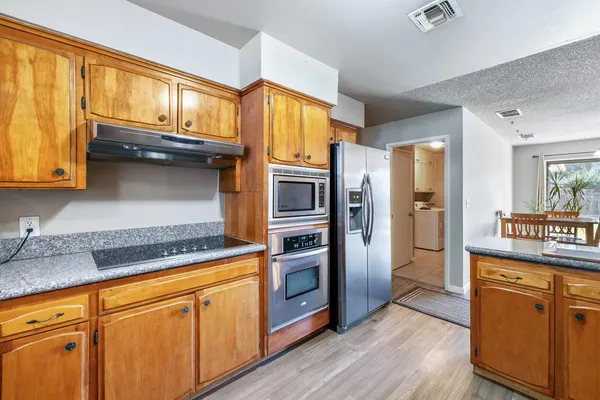 a kitchen with stainless steel appliances granite countertop a refrigerator a stove and a sink with cabinets